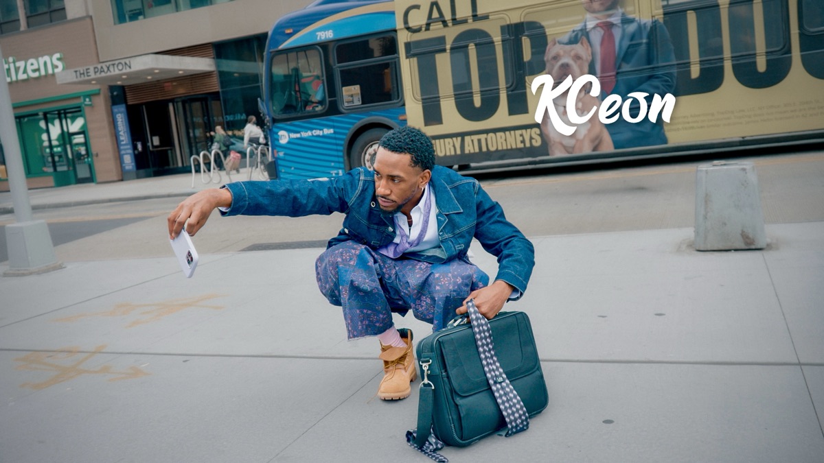 K Ceon crouching on a New York City sidewalk in a denim jacket